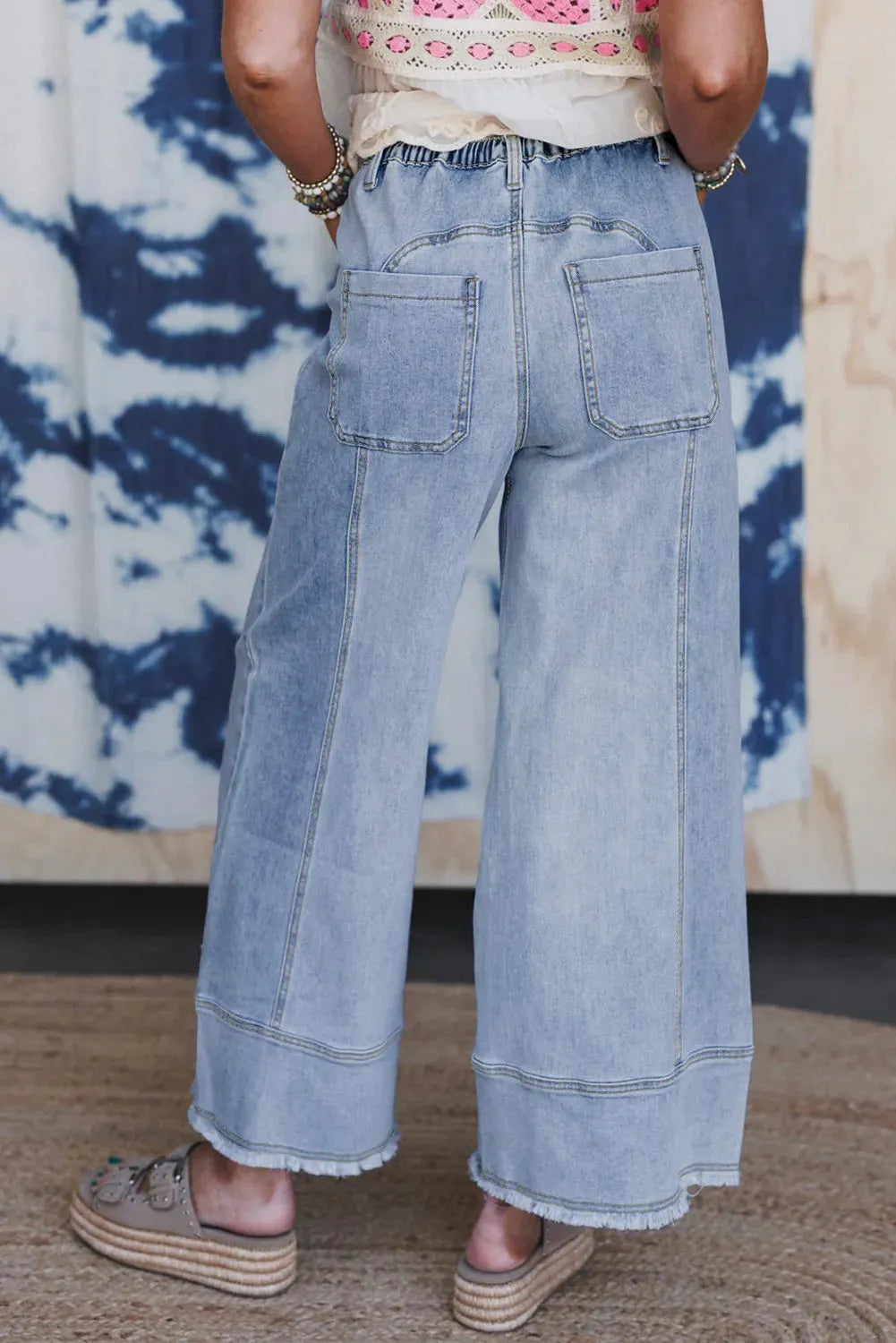 Beau Blue wide leg denim trousers with drawstring waist and raw hem finish laid flat