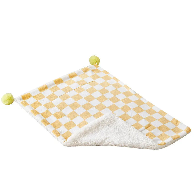 Green plaid pattern plush fleece pet blanket laid flat, showing soft texture and fur ball decoration.