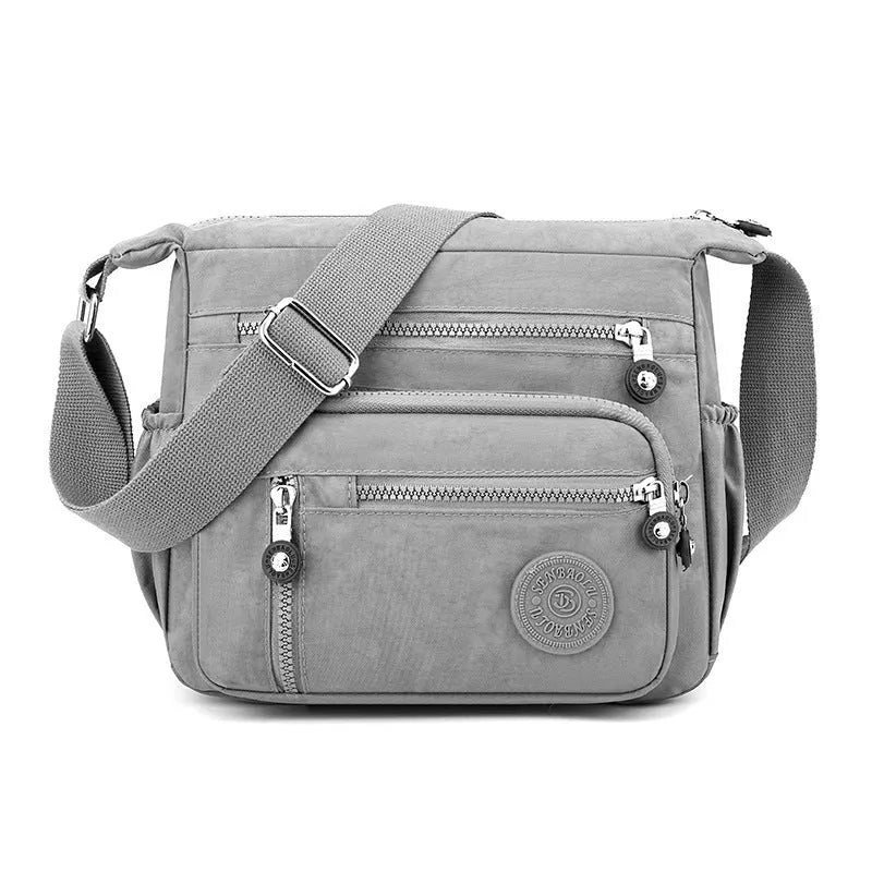 Grey nylon shoulder messenger bag with a single strap and square vertical shape on a neutral background.