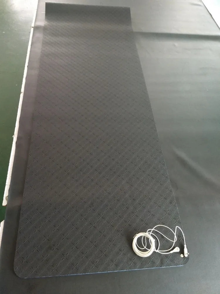 Blue yoga mat with plants pattern and a black grounding wire attached.