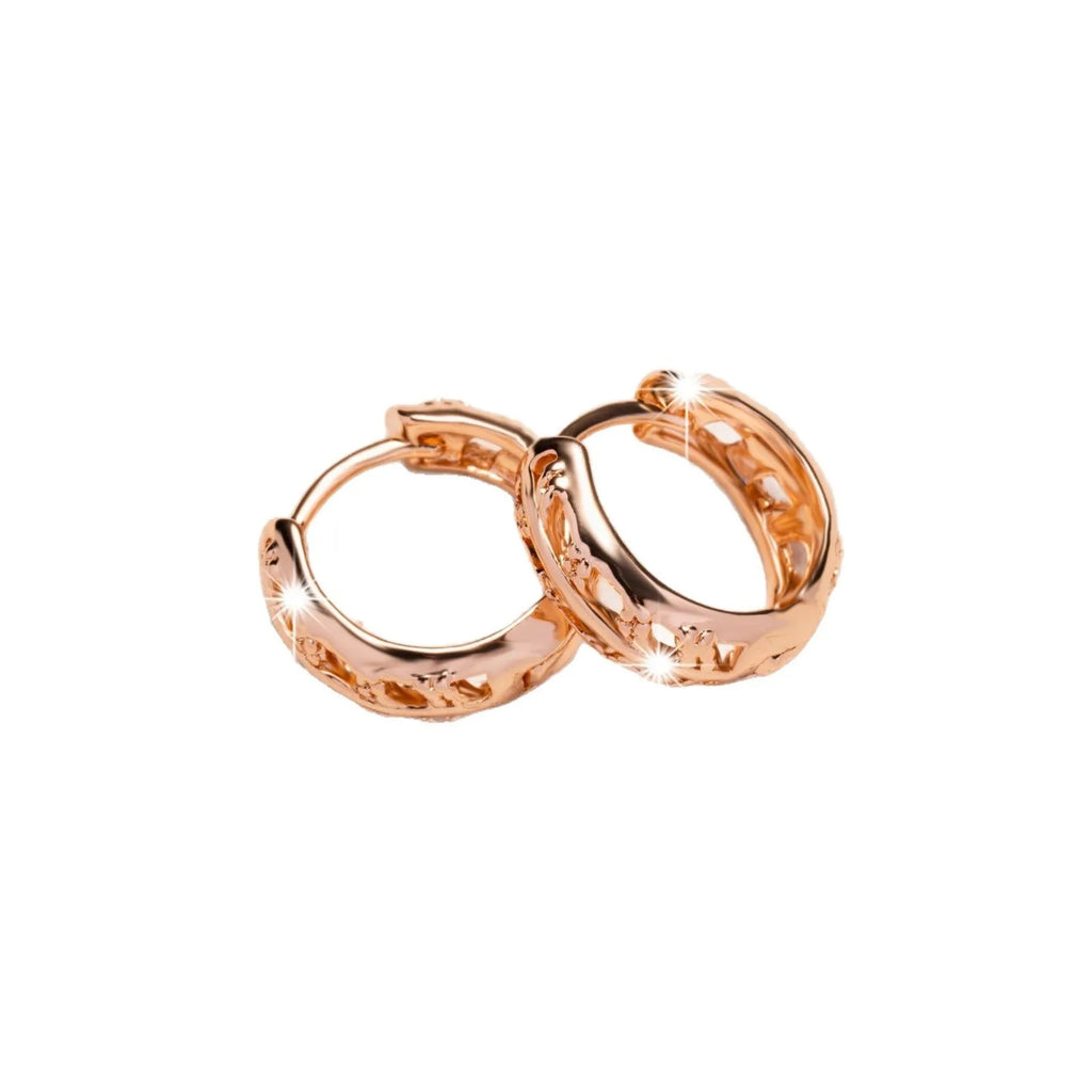 Rose gold hollowed out earrings with heart and leaf shapes on copper background