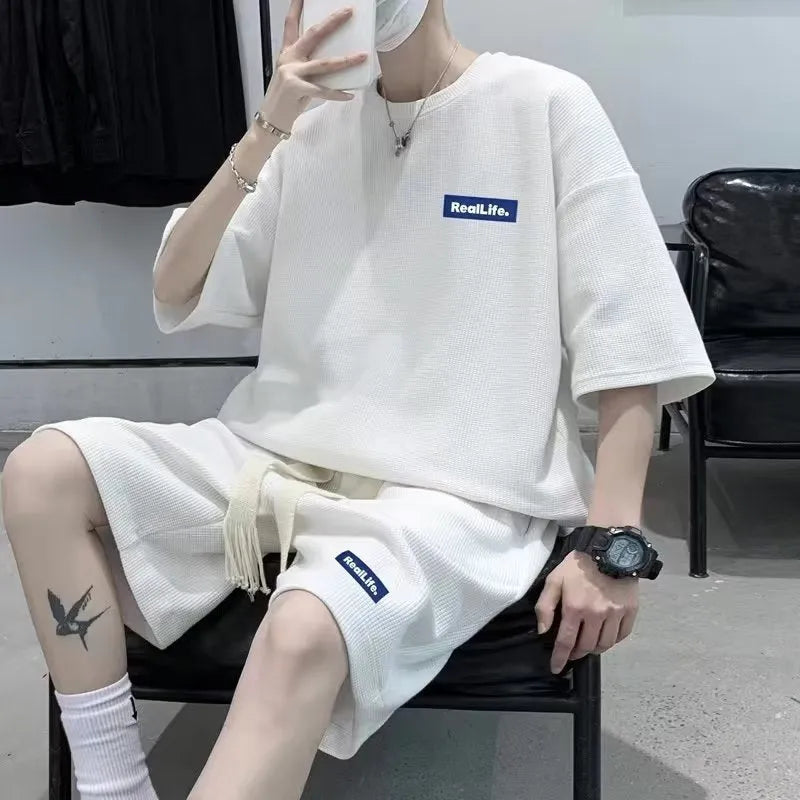 Man wearing a waffle-textured grey cotton short sleeve top and matching shorts from the leisure sport suit set.