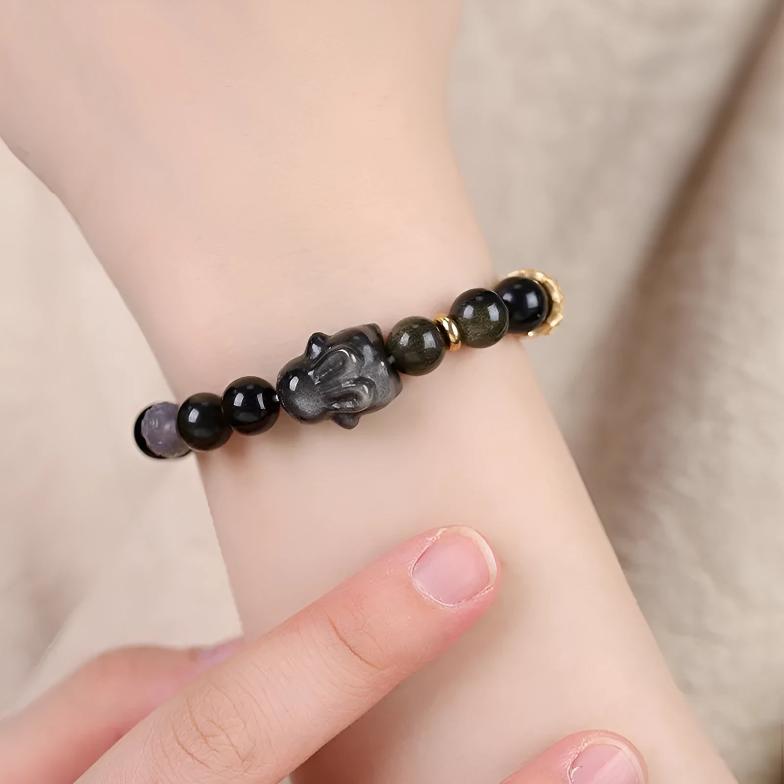 Handmade unisex lying rabbit Jin Yaoshi obsidian bracelet with gray agate and brass beads on neutral background