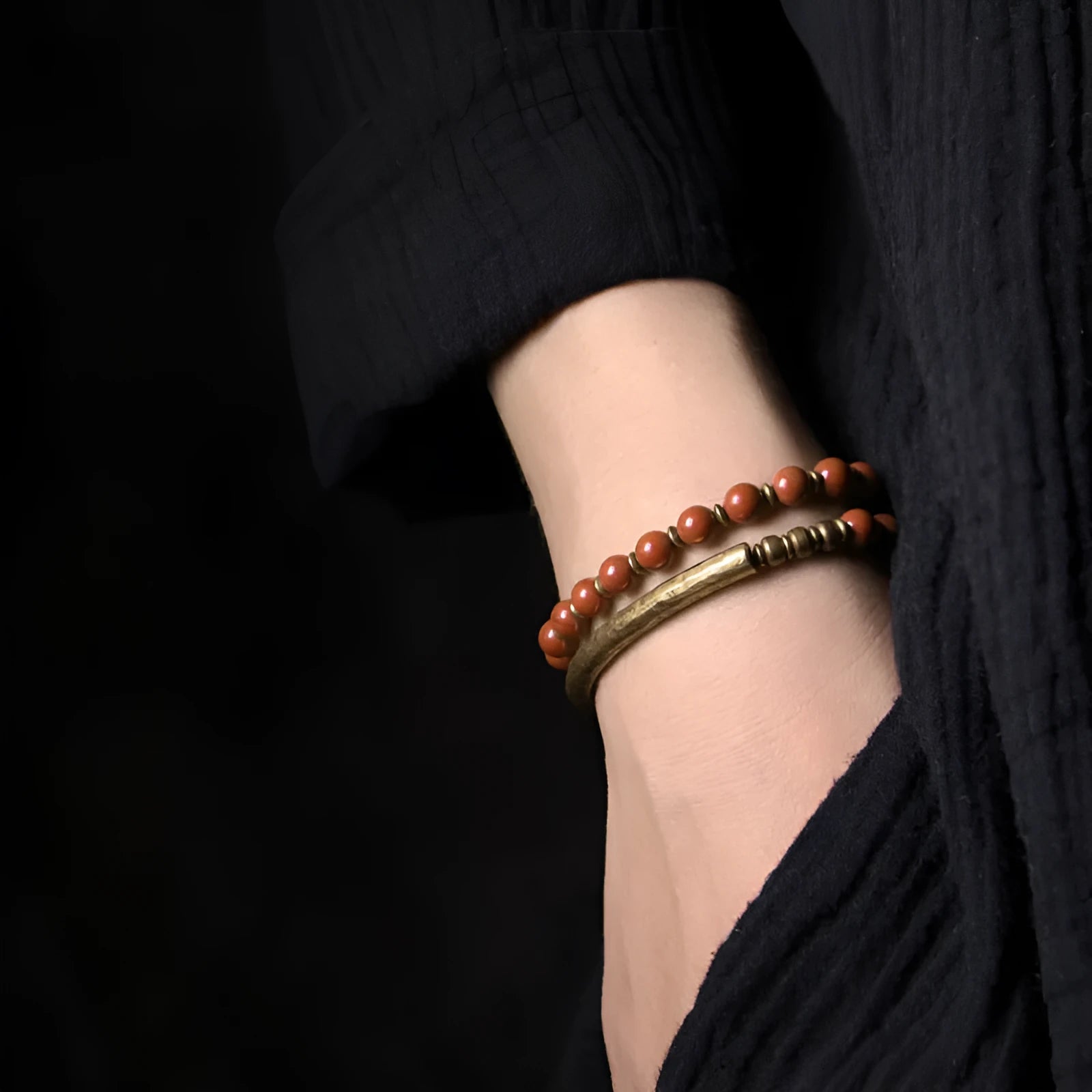 Layered retro ethnic bracelet with water plants agate, obsidian, and red stone beads and brass accents on a neutral background.
