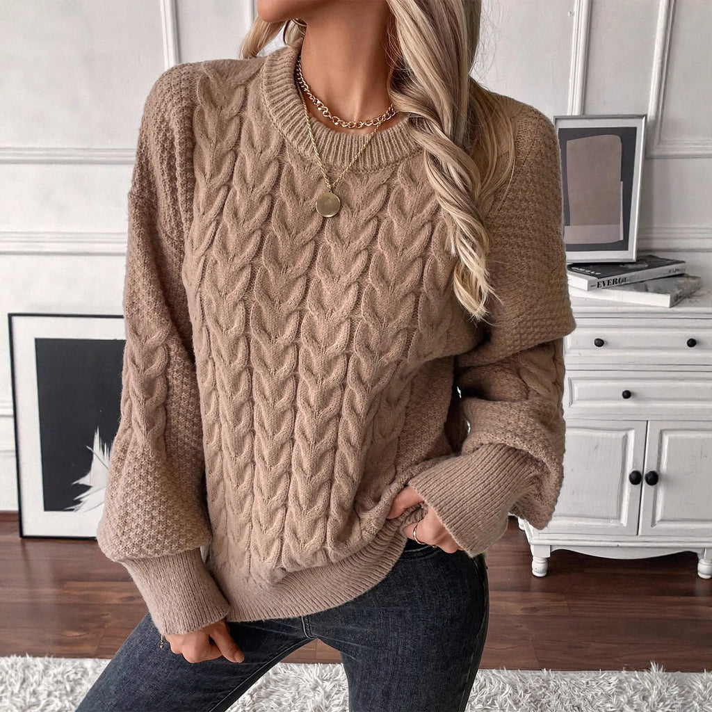 Women's loose beige pullover sweater with a twist detail and round neck on a hanger.