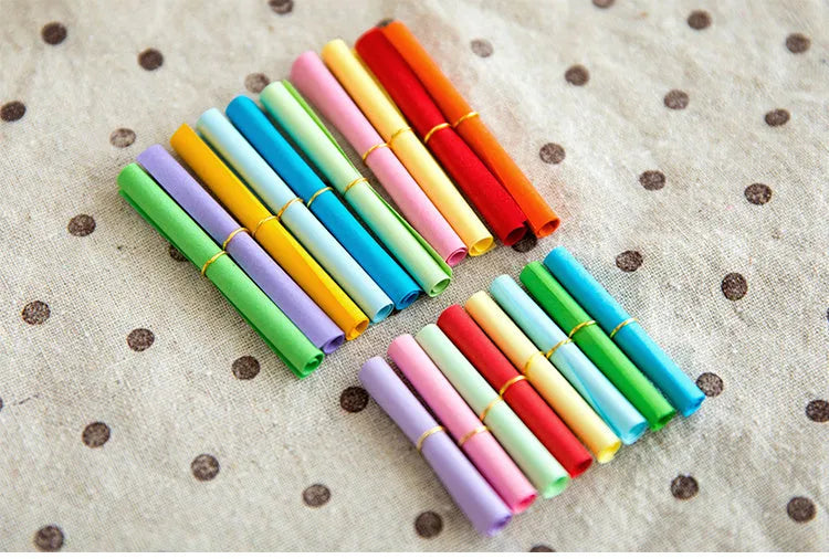 Assorted colour mini paper scrolls with metal eyelets in sizes 5x5cm, 3x7cm, 4x7cm, and 7x7cm for drift bottle messages.