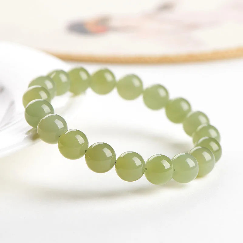 Polished Hetian jade ball bracelet in clear water colour on a wrist, showing spherical beads.
