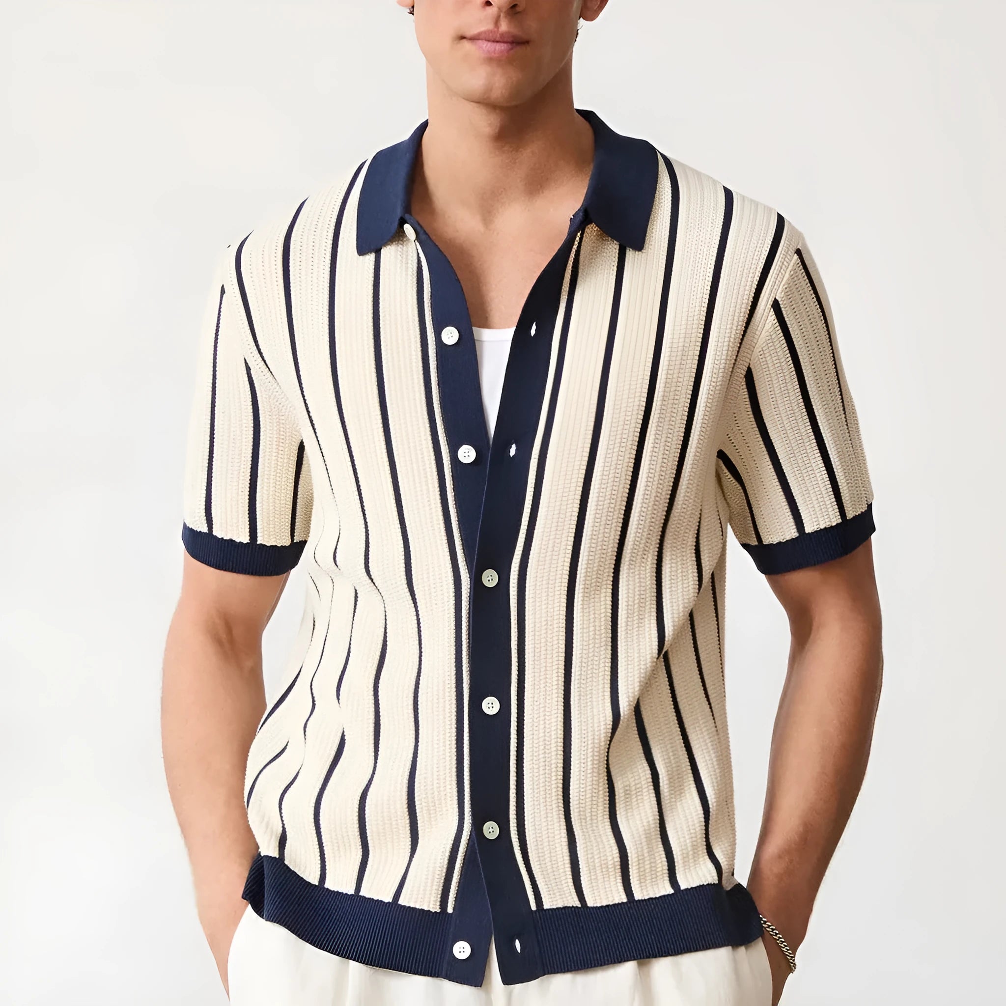 Man modelling a white short sleeve knitted top with asymmetric stripes and a lapel collar.