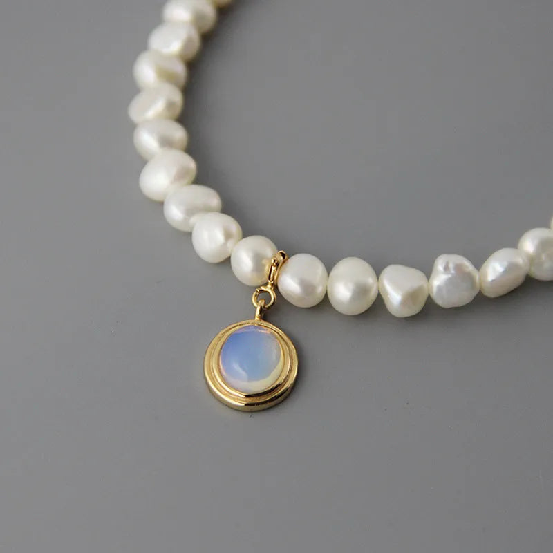 Close-up of a round 925 sterling silver necklace with an irregular geometric pearl pendant on a white background.