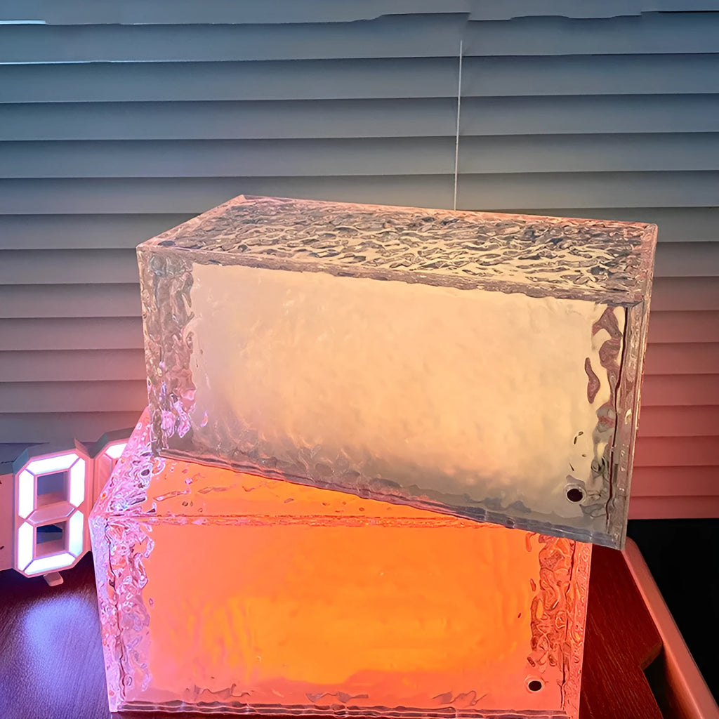 Small modern geometric acrylic night lamp with coloured LED light on a wooden surface.