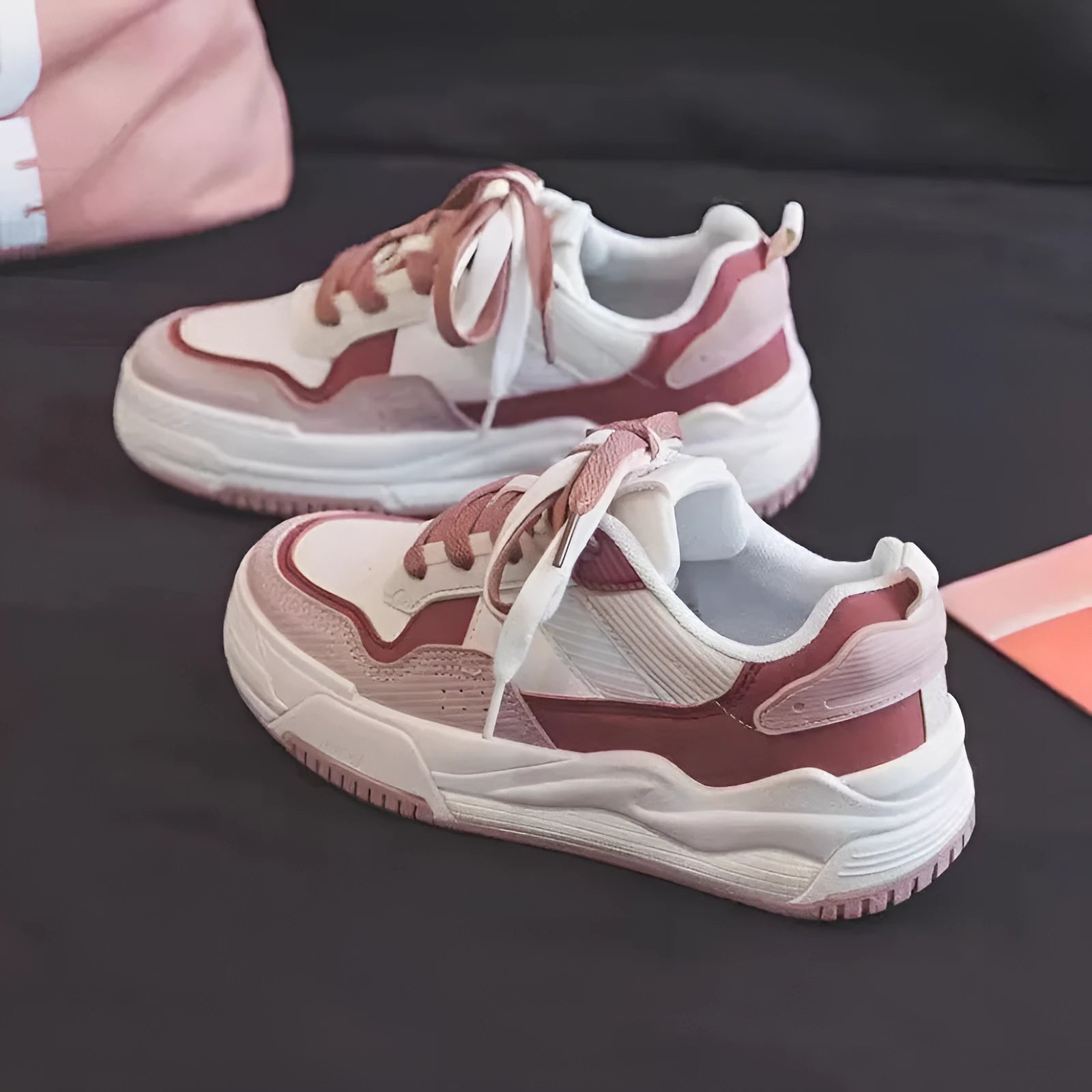 Women's low-top pink and white sneakers with a rubber sole and imitation leather lining.