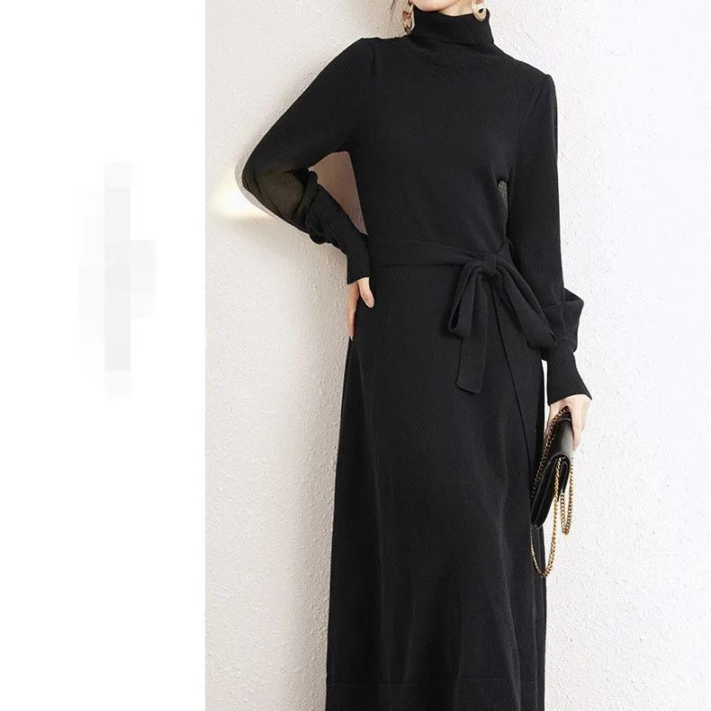 Adult lady wearing a solid colour knitted turtleneck dress with long sleeves, a loose mid-length skirt, and an elastic waist.
