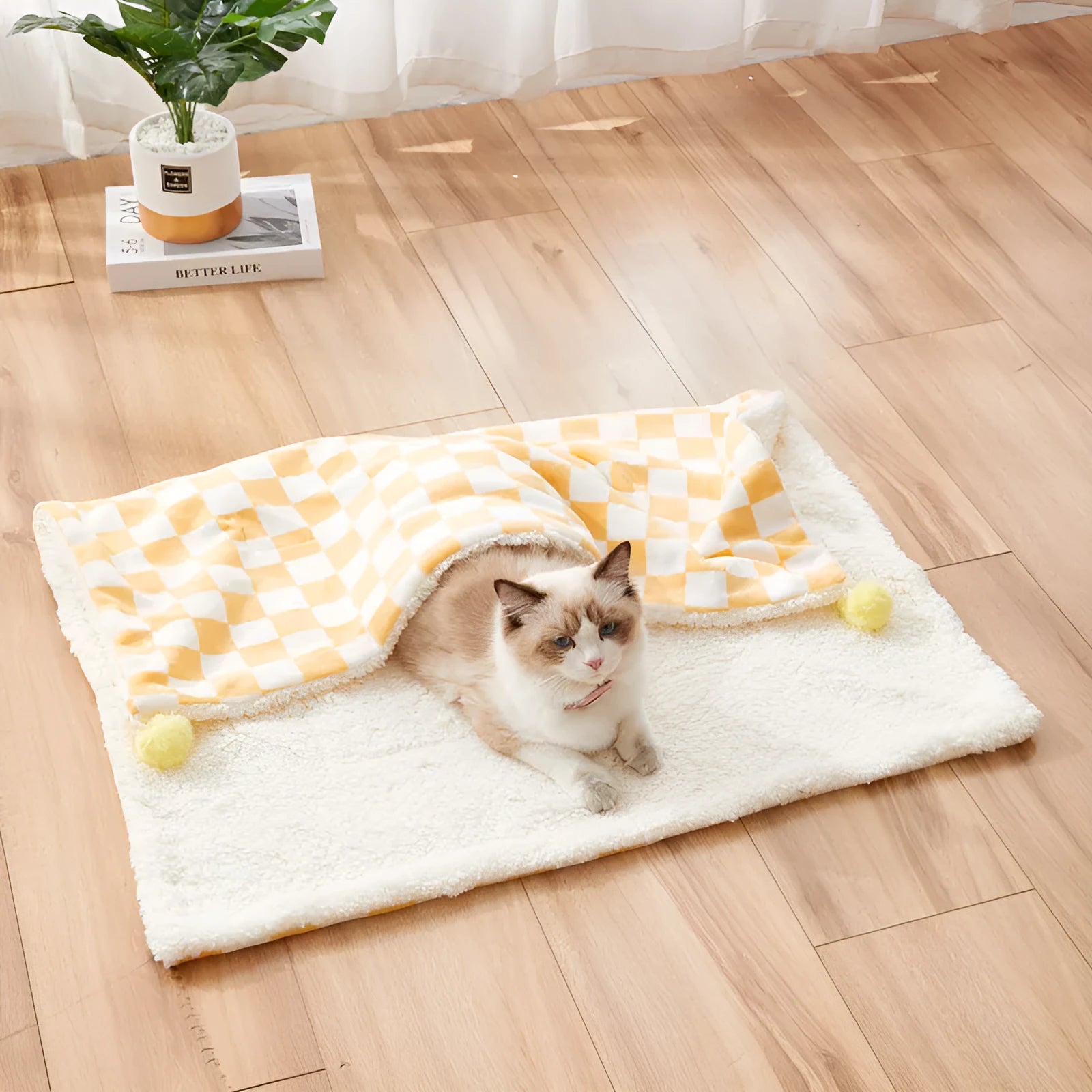 Green plaid pattern plush fleece pet blanket laid flat, showing soft texture and fur ball decoration.