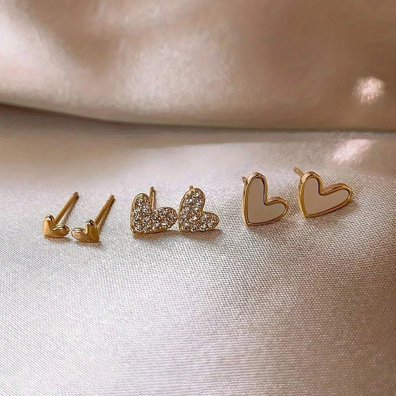 Three pairs of heart-shaped girly drop earrings in gold, black, pink colours
