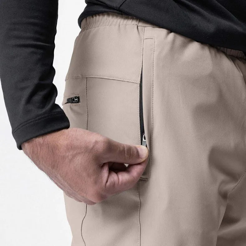 Man wearing dark grey quick-dry fitness trousers with ankle ties, suitable for running and gym workouts.