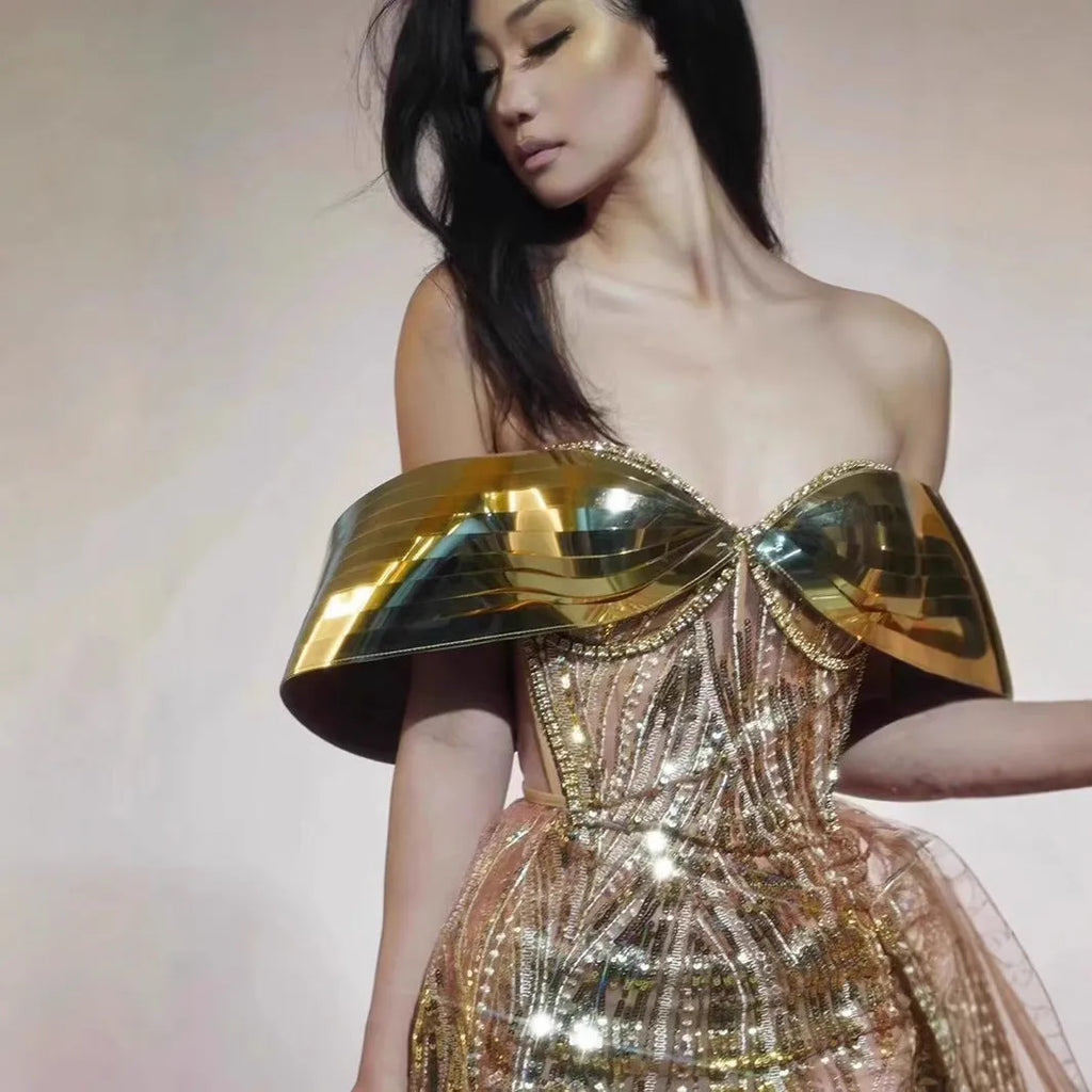 Gold sequined strapless long dress with a side split and tube top, shown on a model.
