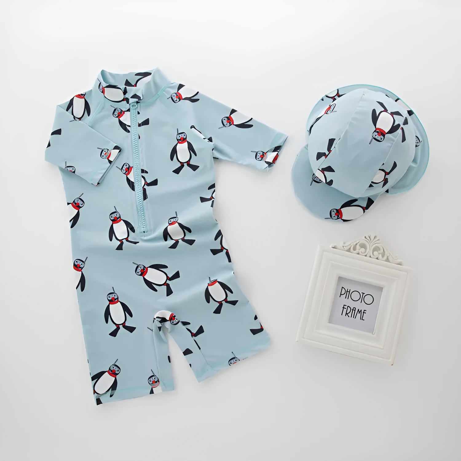 Boys' long-sleeve penguin print swimsuit set with matching swimming cap on mannequin