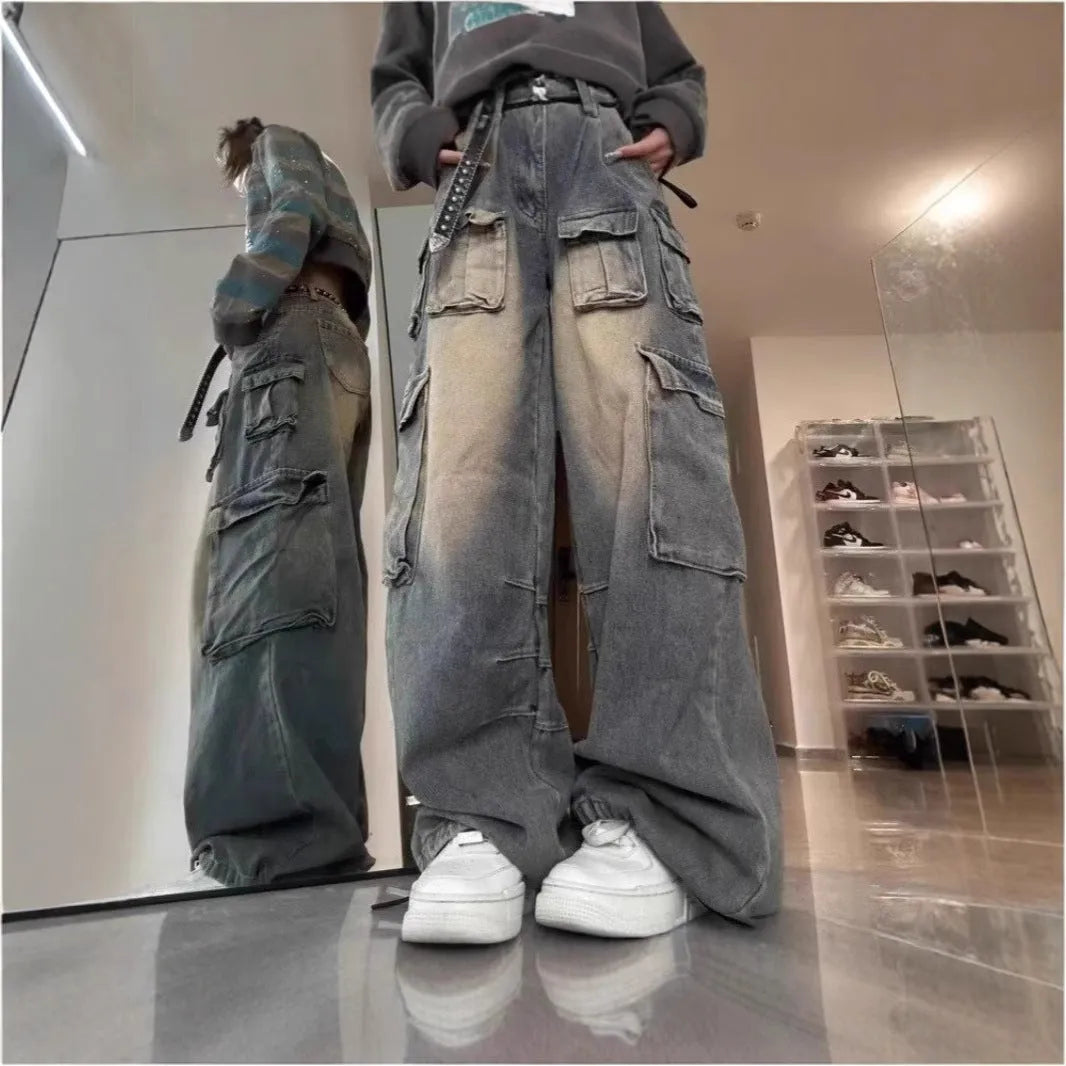 Man wearing loose fit light blue distressed jeans with multiple tooling pockets and straight leg silhouette.