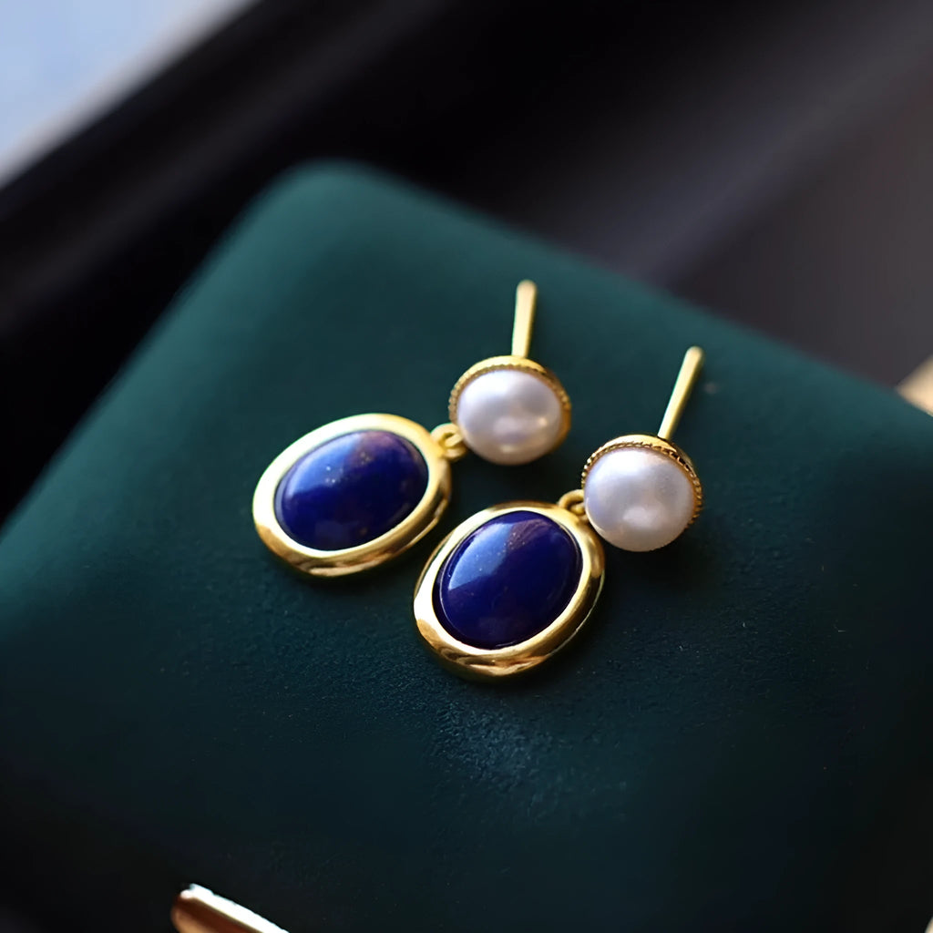 A pair of simple 925 silver earrings with a blue lapis lazuli pearl and auspicious pattern details.