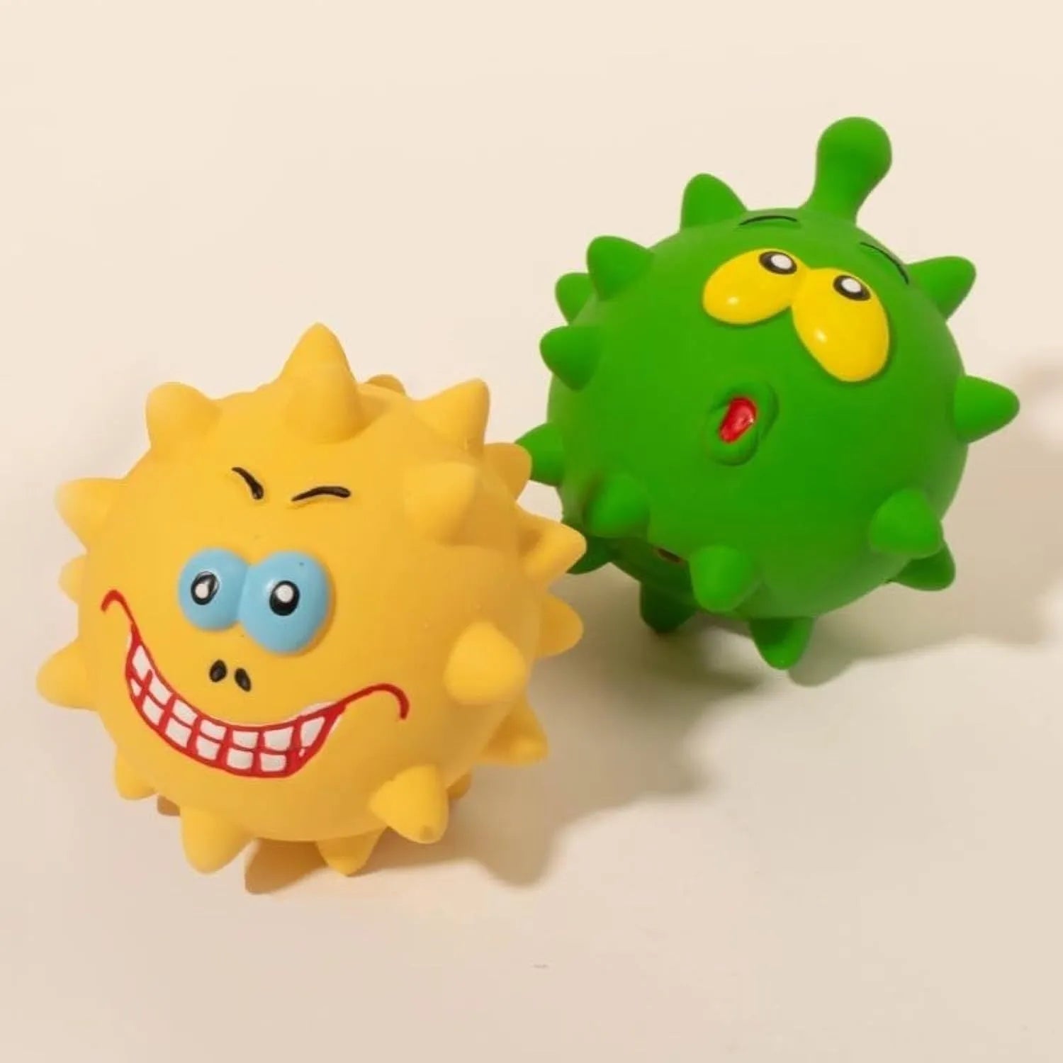Set of four colourful latex squeaky dog balls with cute faces and textured surfaces.