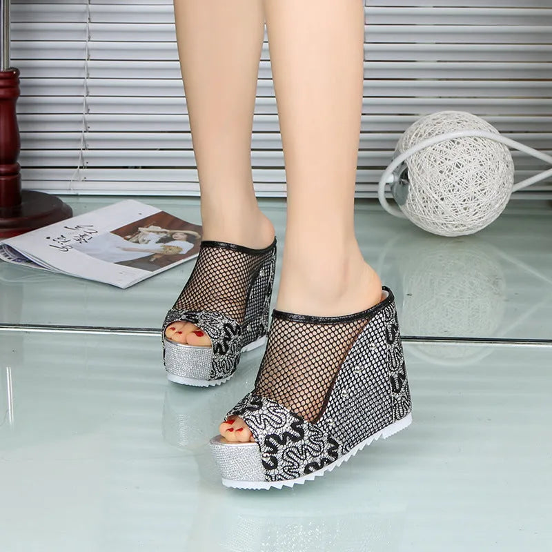 Black platform flip-flops with a chunky heel, hollowed-out design, and mesh upper on a white background.