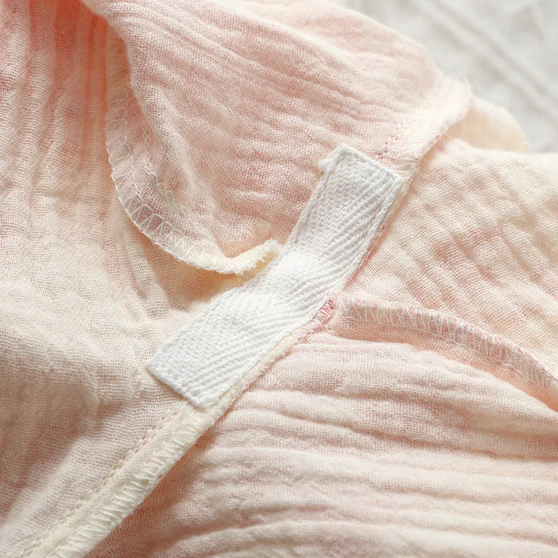Women's pink pure cotton gauze suit with long sleeves and lace-up trousers on a hanger.