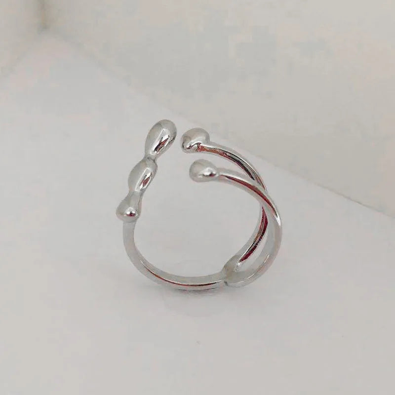 Brass opening ring with spherical element in gold colour on a hand.