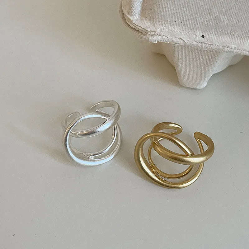 Geometric open ring for women with three-dimensional interlaced matte metal design in gold or silver.