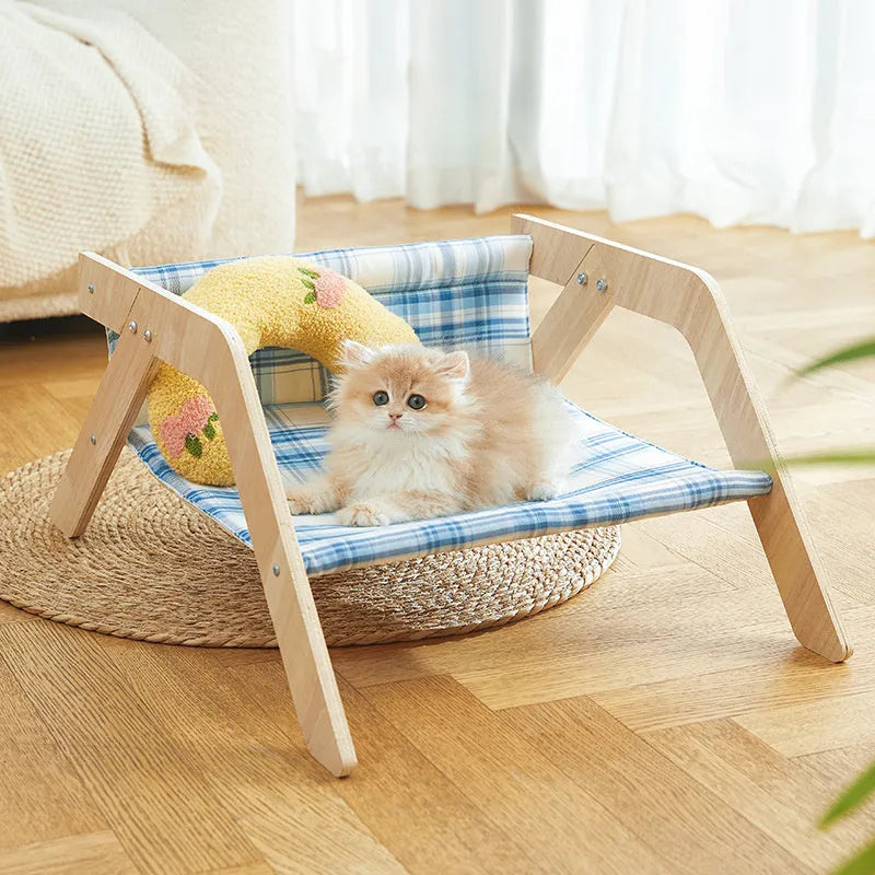 Elevated wooden cat bed with blue cloth hammock surface on a wooden floor