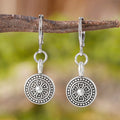 Close-up of a pair of women's geometric round bohemian retro style earrings with a distressed ethnic design in zinc alloy.