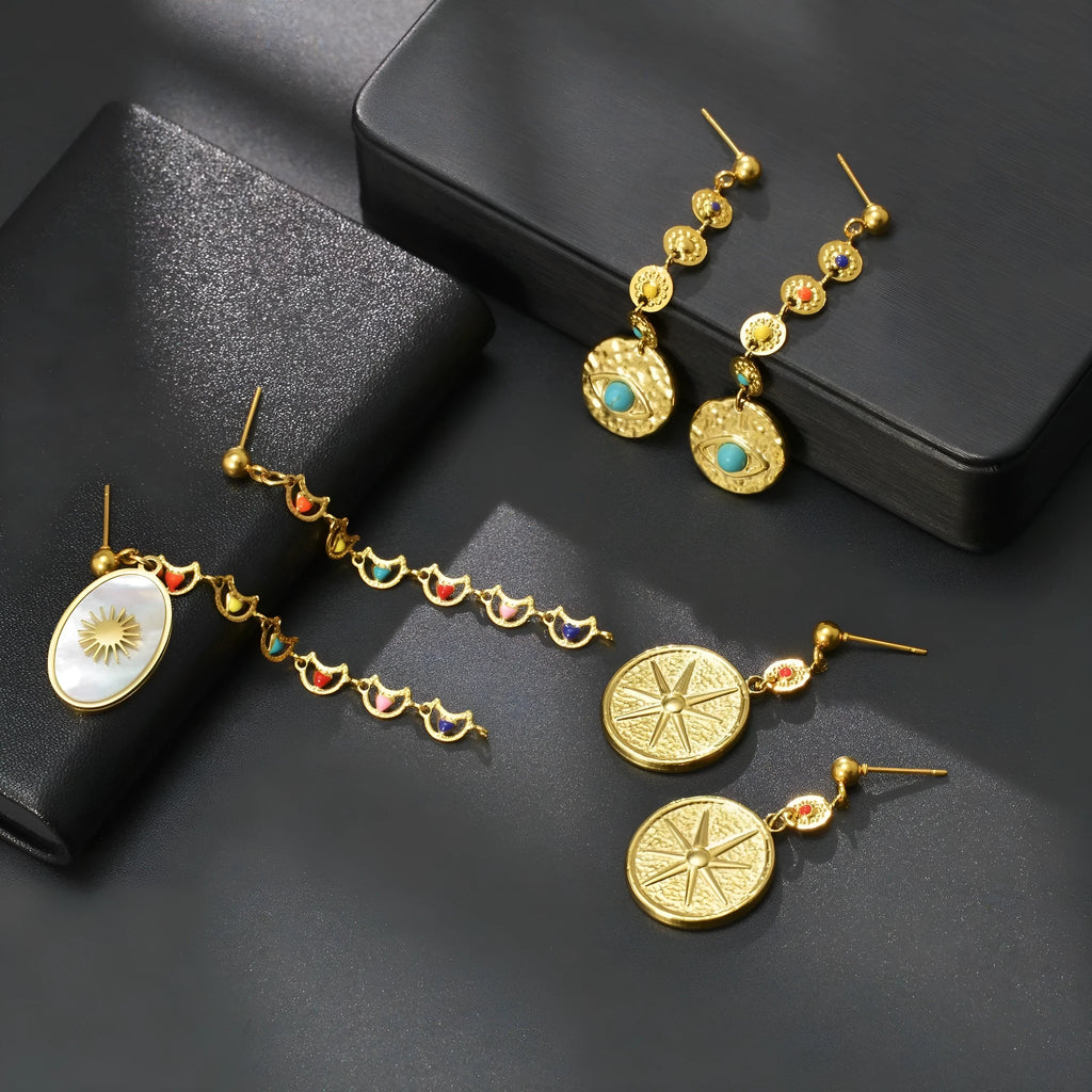 Three pairs of geometric stainless steel earrings: eight-point star, eye motif and shell sun designs