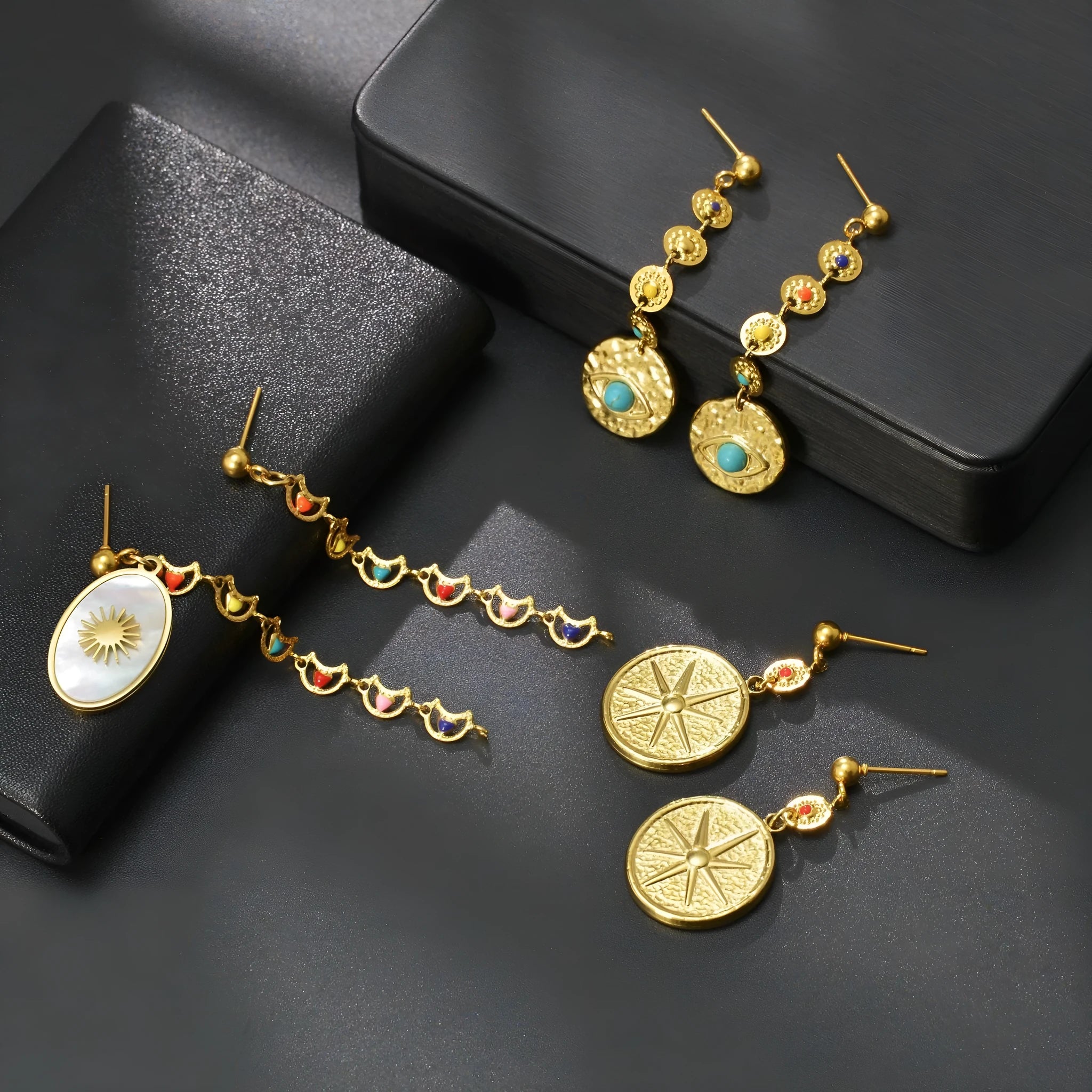 Three pairs of geometric stainless steel earrings: eight-point star, eye motif and shell sun designs