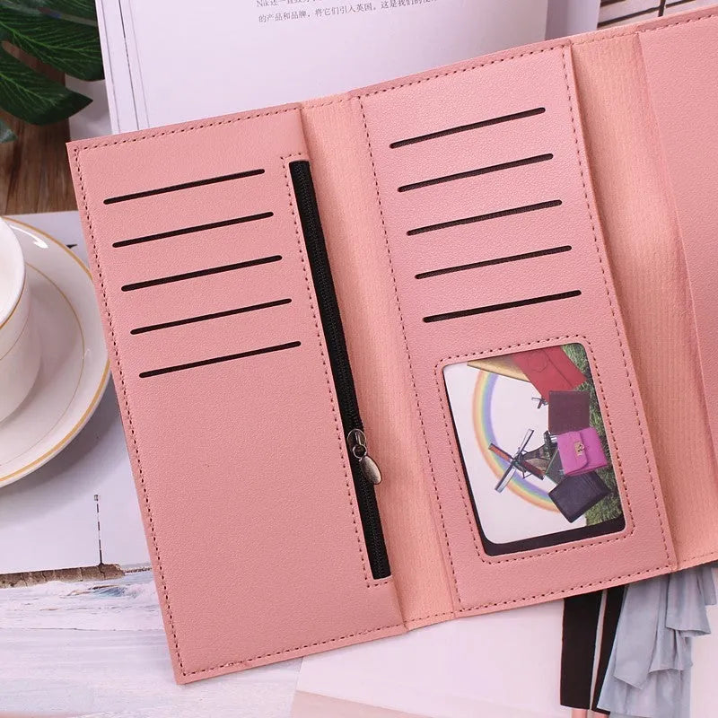 Women's long tri-fold wallet in light grey PU leather with sewing thread detail, open to show multiple card slots and cash compartments.