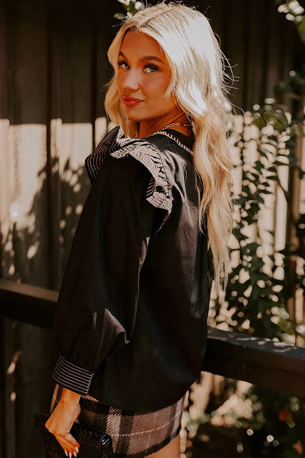 Black women's long sleeve blouse with v-neck ruffle detail and white contrast stitching