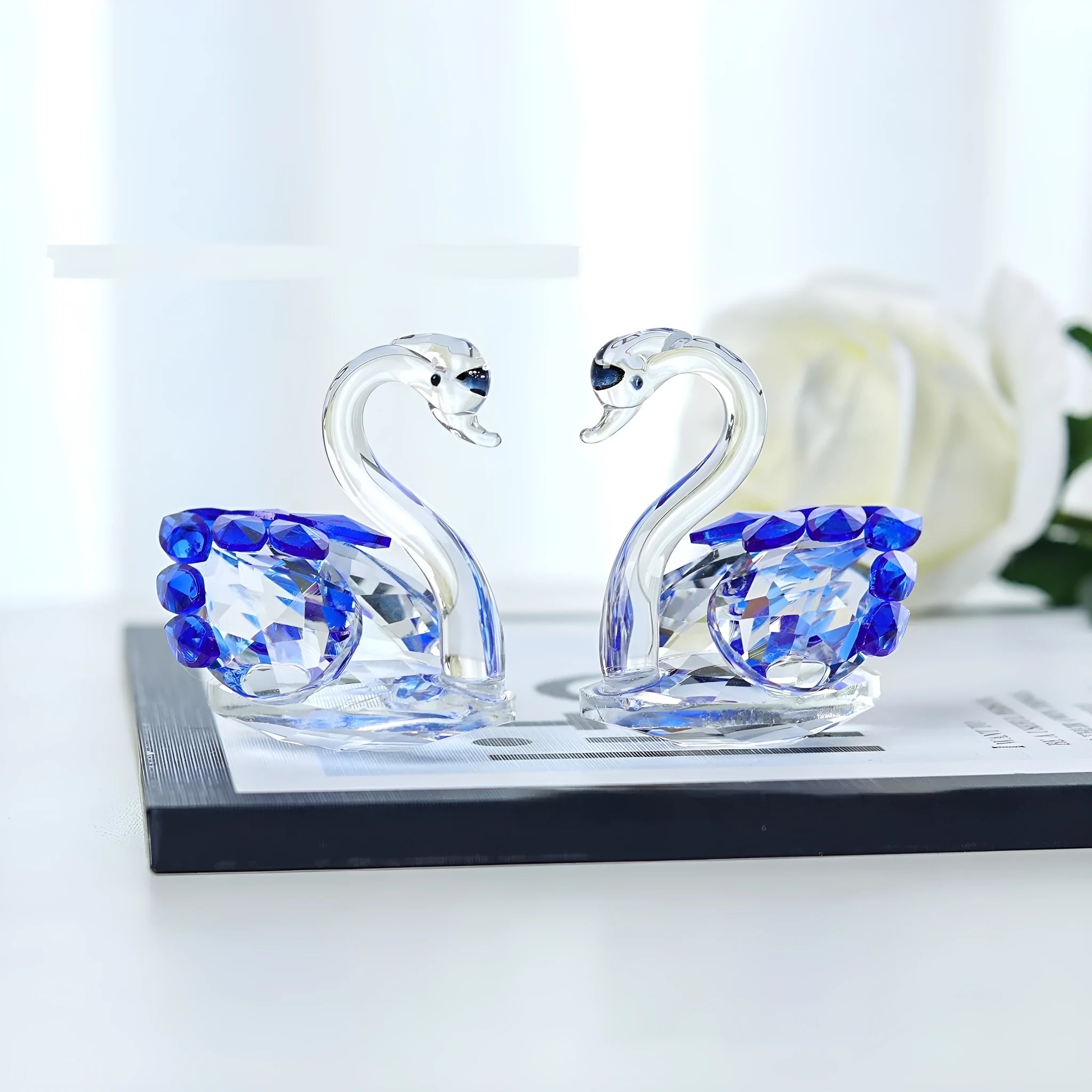 White crystal swan desktop ornament in red, blue, pink, or purple on a wood surface.