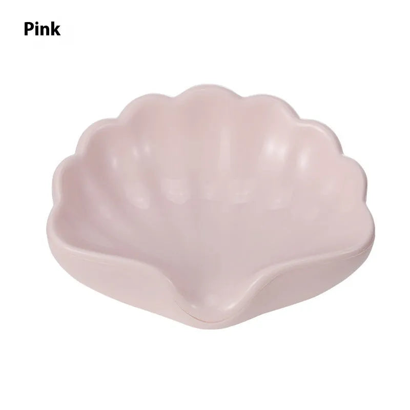 White plastic shell-shaped soap dish with a raised centre, placed on a bathroom counter.