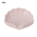 White plastic shell-shaped soap dish with a raised centre, placed on a bathroom counter.