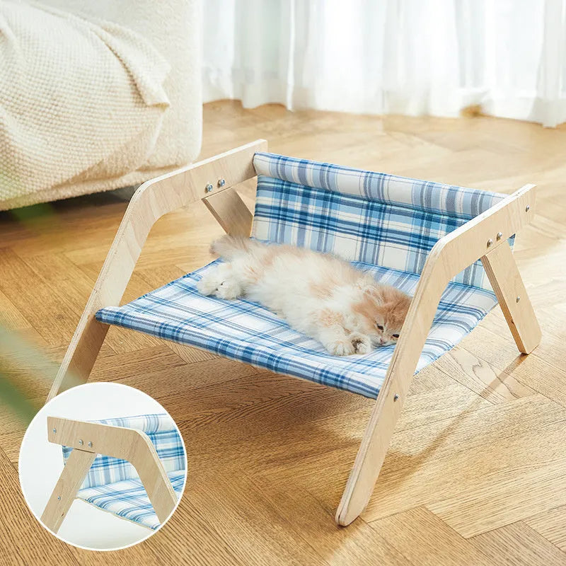 Elevated wooden cat bed with blue cloth hammock surface on a wooden floor