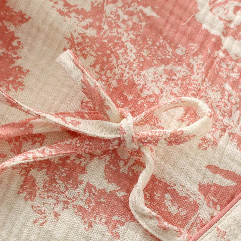 Women's pink pure cotton gauze suit with long sleeves and lace-up trousers on a hanger.