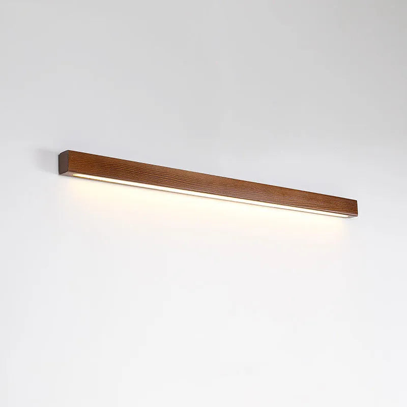 Slim walnut-colour wood and acrylic LED strip wall lamp in three length options on a white wall.