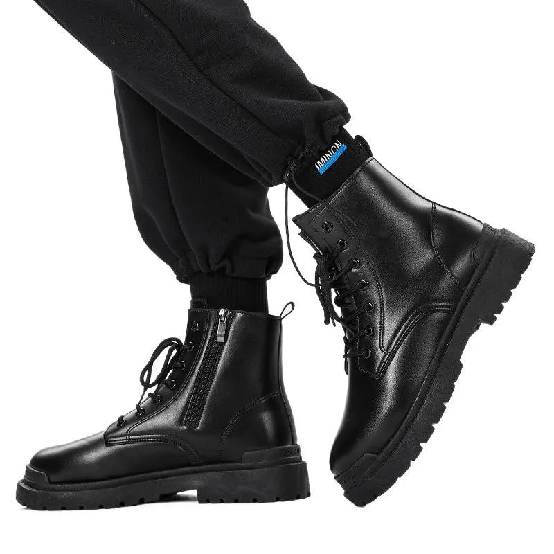 Men's black mid-top leather lace-up boots with a rubber sole on a wooden floor