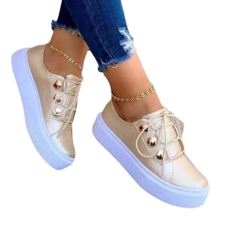 Women's white lace-up flats sneakers with silver rivet detailing on a low round toe.