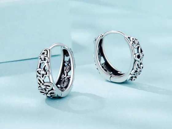 Pair of sterling silver hollow butterfly earrings with zircon accents, showing retro design.