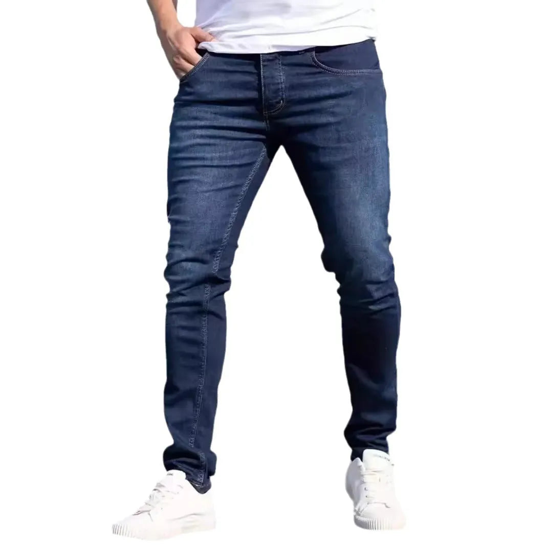 Dark blue men's slim fit cotton jeans with a skinny leg opening on a mannequin
