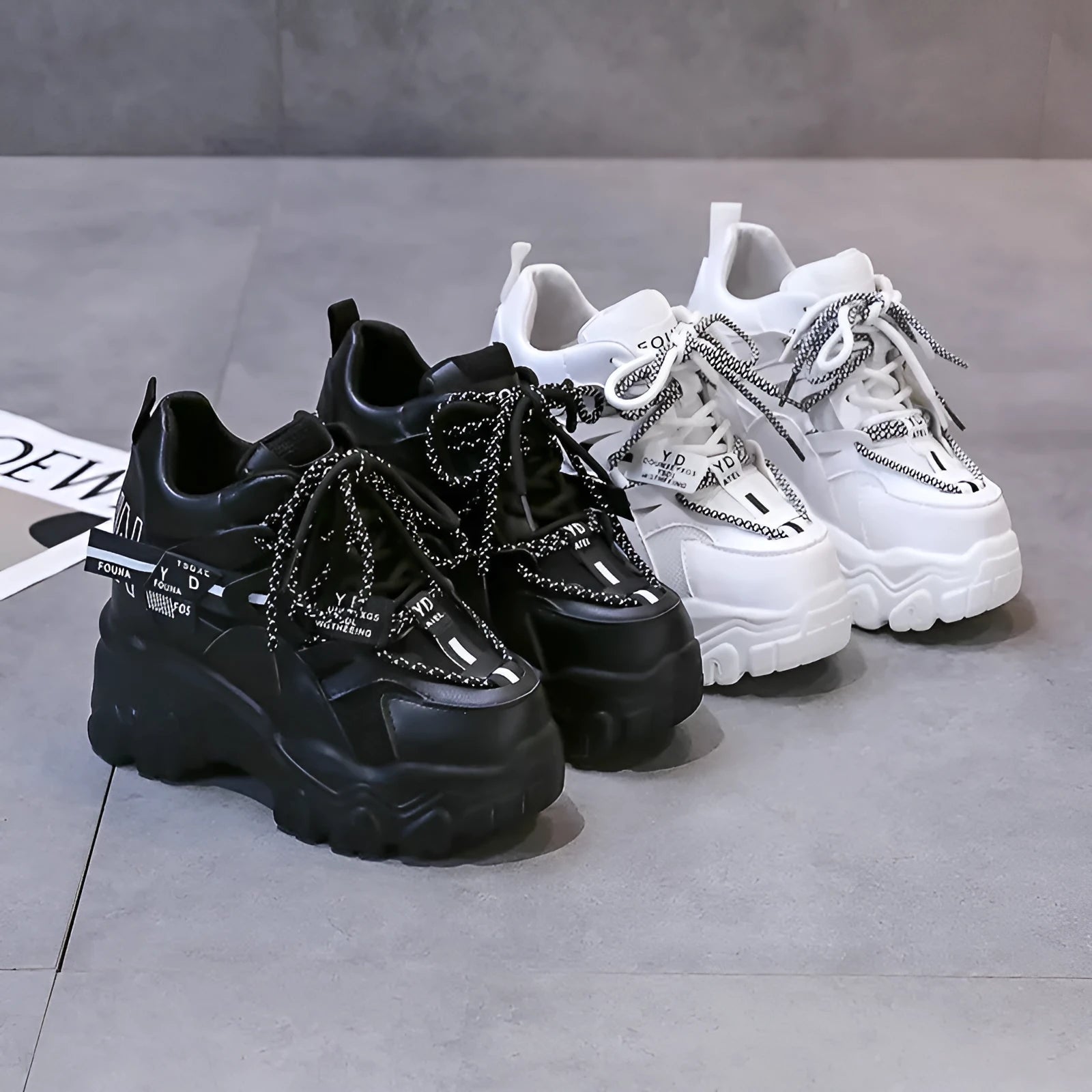 White and black women's low-top platform sports shoes with cross-strap and mesh design on a rubber sole.