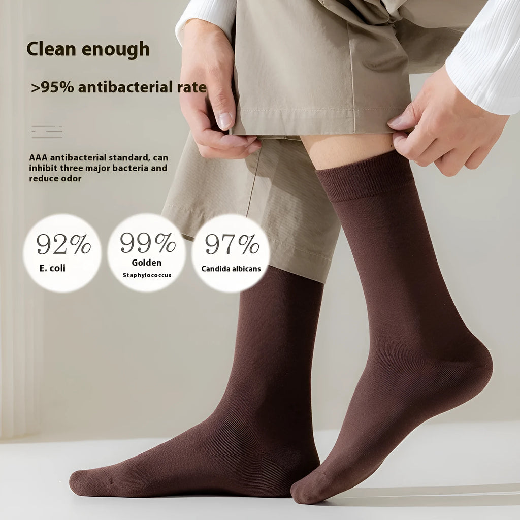 Pack of men's solid colour mid-calf business socks in combed cotton on a neutral background.