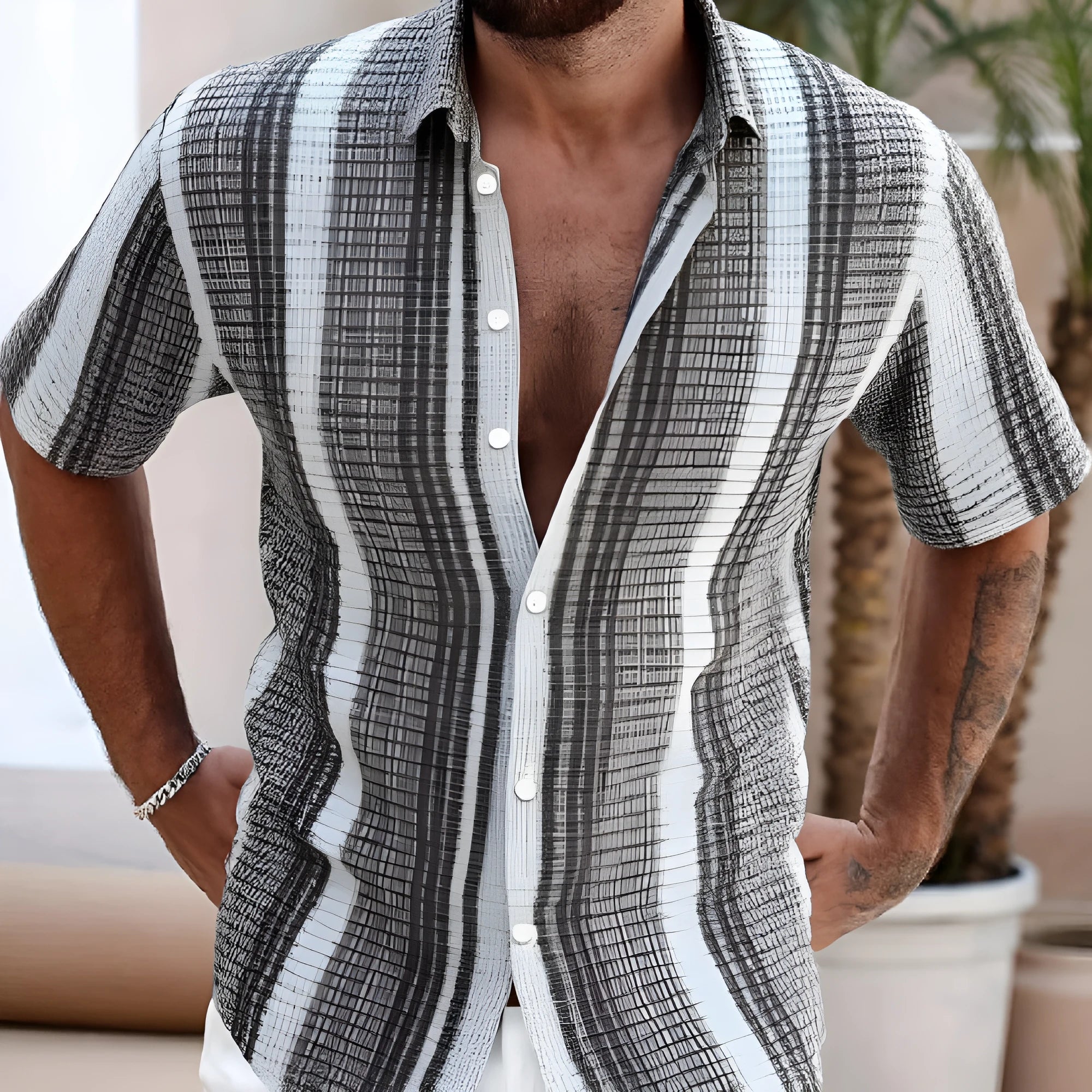 Man wearing a slim fit short sleeve shirt with a colourful 3D floral print, on a beach.