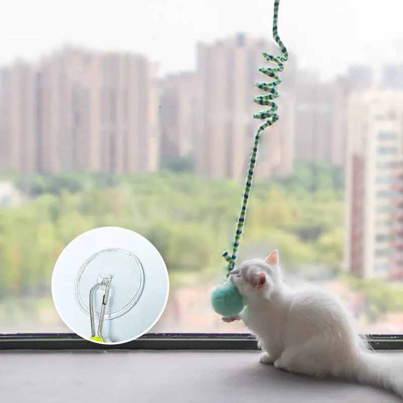 Cat toy with inflatable ball and bell stick hanging from door with suction cup attachment