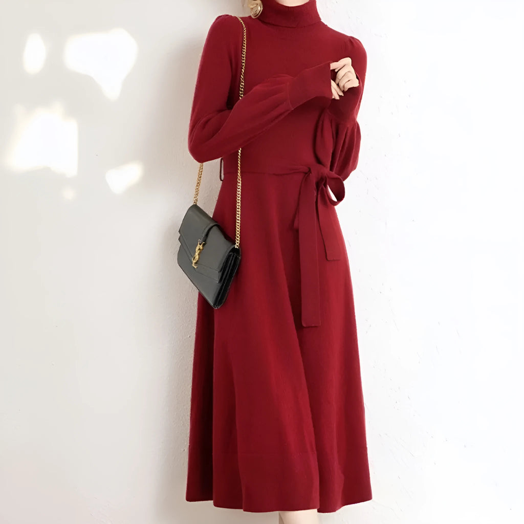 Adult lady wearing a solid colour knitted turtleneck dress with long sleeves, a loose mid-length skirt, and an elastic waist.