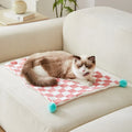 Green plaid pattern plush fleece pet blanket laid flat, showing soft texture and fur ball decoration.